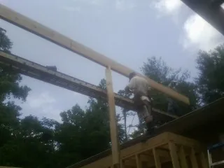 Carpenter setting a ridge beam over a new addition frame — Ice Dam Removal by Roofing Brothers in Bigfork