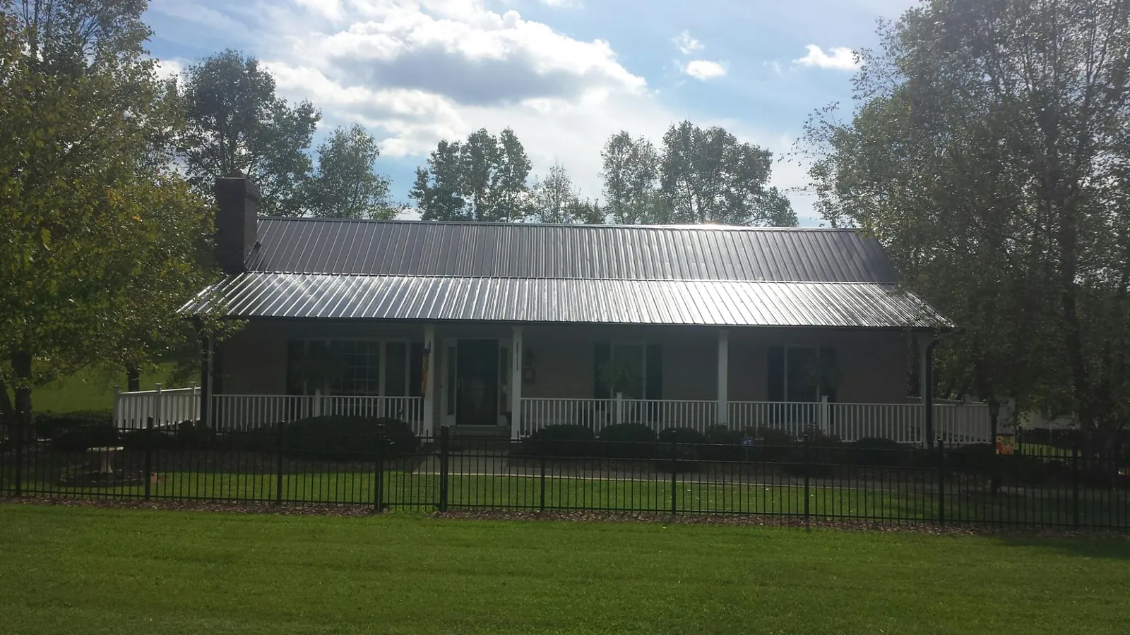 Gray metal roof on a brick ranch with a full width front porch — Gutter Guard Installation work by our crew in Bigfork