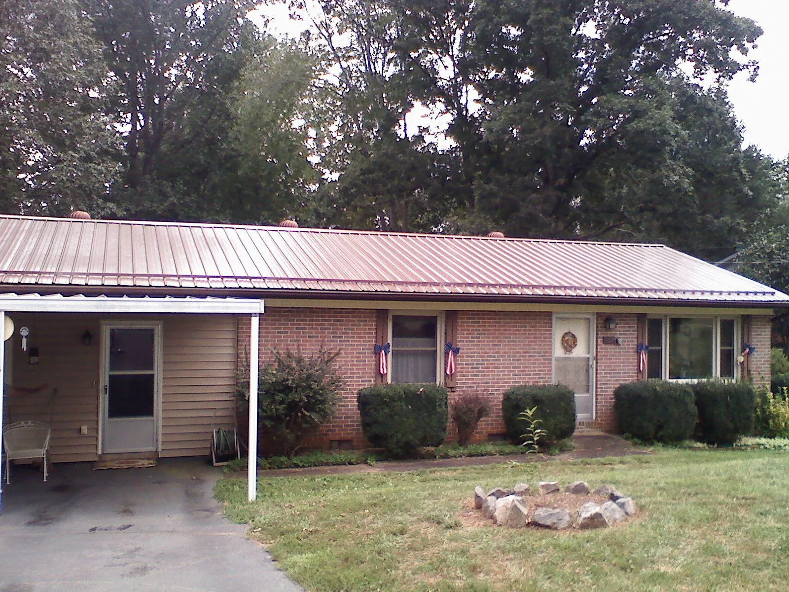 Bronze metal roof and carport on a brick ranch home — Roof Repair work by our crew in Bigfork